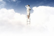 Businesswoman standing on ladder