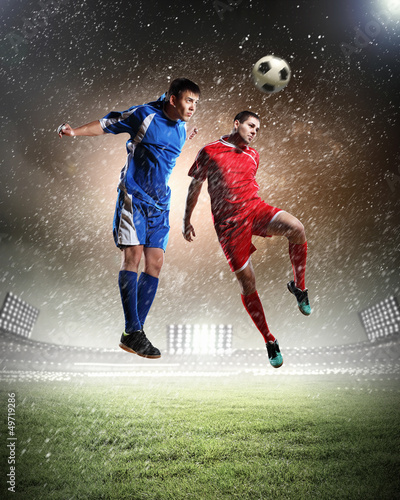 Photo: two football players striking the ball two football players striking the ball