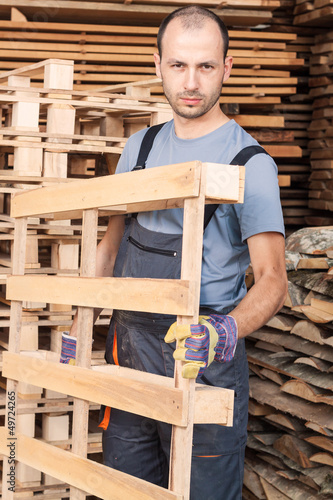 Photo: Warehouse worker moving wood pallets Warehouse worker moving wood pallets