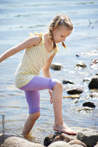 Photo: Girl goes to shore of water in sunny day Girl goes to shore of water in sunny day