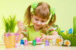 cute smiling child girl painting Easter eggs on green background