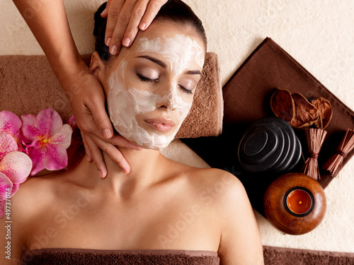 Photo: Spa massage for woman with facial mask on face Spa massage for woman with facial mask on face