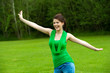 Cute girl with open arms in green field.