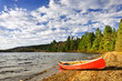 Red canoe on lake shore