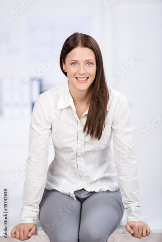 Photo: junge frau sitzt auf dem schreibtisch junge frau sitzt auf dem schreibtisch