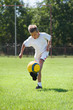 boy kicking football outside