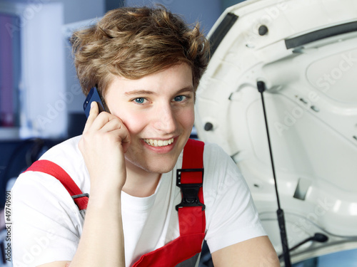Photo: Car mechanic in a garage calls a customer Car mechanic in a garage calls a customer