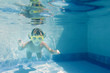 young child girl swimming underwater in pool