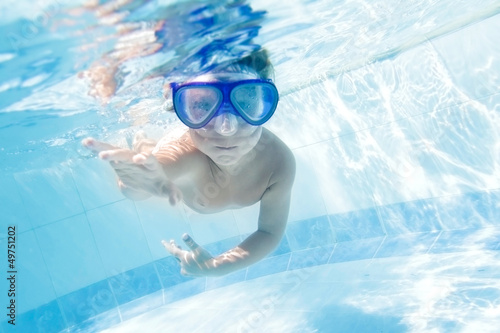 Photo: young child swimming underwater in pool young child swimming underwater in pool