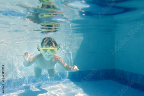 Photo: young child girl swimming underwater in pool young child girl swimming underwater in pool