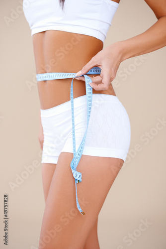 Photo: Close up of a woman she measuring her waist Close up of a woman she measuring her waist