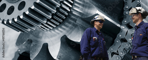 Photo: engineers with giant cog-machinery in background engineers with giant cog-machinery in background