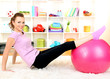 Young woman doing fitness exercises with gym ball at home