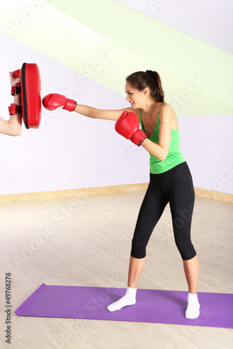 Photo: Young beautiful woman with boxing gloves at workout, at gym Young beautiful woman with boxing gloves at workout, at gym