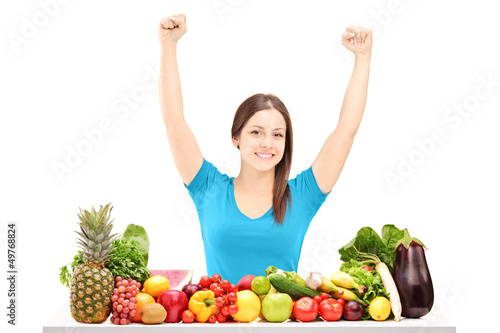 Photo: Beautiful young female gesturing happiness on a table full of fr Beautiful young female gesturing happiness on a table full of fr