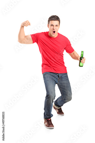 Photo: Full length portrait an euphoric fan holding a beer bottle and c Full length portrait an euphoric fan holding a beer bottle and c