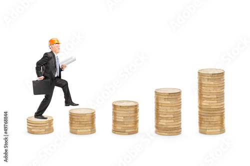 Photo: Full length portrait of a male engineer with blueprints walking Full length portrait of a male engineer with blueprints walking