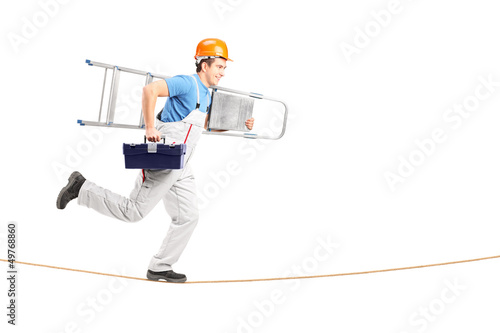 Photo: Full length portrait of a repairman running on a rope with a lad Full length portrait of a repairman running on a rope with a lad