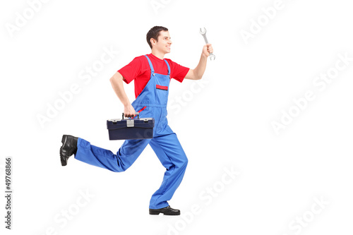 Photo: Full length portrait of a repairman running with a wrench and a Full length portrait of a repairman running with a wrench and a