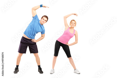 Photo: Full length portrait of a young male and female exercising Full length portrait of a young male and female exercising
