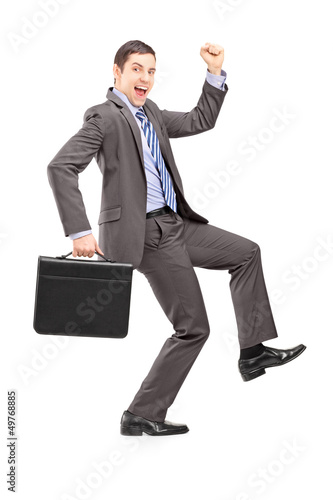 Photo: Full length portrait of an excited businessman with a briefcase Full length portrait of an excited businessman with a briefcase