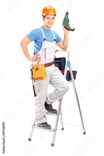 Photo: Full length portrait of a repairman with a hand drilling machine Full length portrait of a repairman with a hand drilling machine
