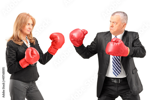 Photo: Mature businesswoman with boxing gloves having a fight with a bu Mature businesswoman with boxing gloves having a fight with a bu