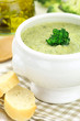 Creamy broccoli soup in a white bowl served with some bread