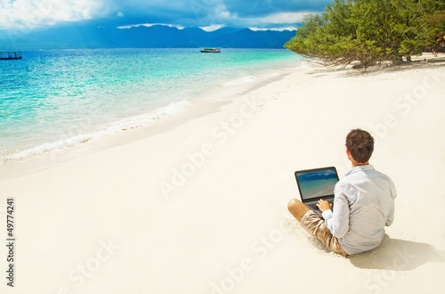 Photo: man with laptop on colorful beach of island man with laptop on colorful beach of island