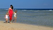 Family with children holding hands walking on the beach.