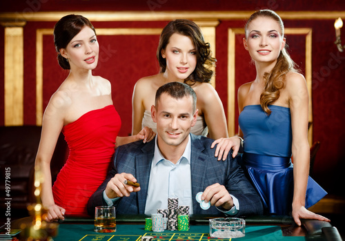 Photo: Man surrounded by women gambles roulette at the casino Man surrounded by women gambles roulette at the casino