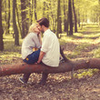 happy young couple kissing and hugging, sitting on a tree happy young couple kissing and hugging, sitting on a tree