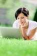 Girl lying on the grass works at the silver laptop