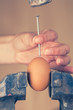 Detail of a Hand Trying to Break an Egg with a Nail (color toned