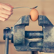 Detail of Hand with Spoon Tapping an Egg Fixed in Vice (color to