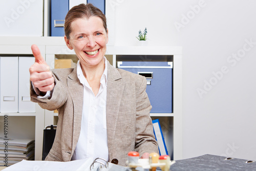 Photo: Seniorin im Büro hält Daumen hoch Seniorin im Büro hält Daumen hoch