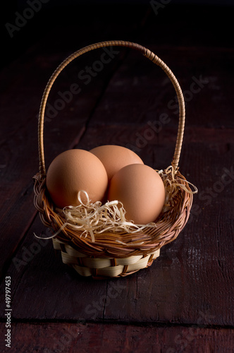 Photo: Easter eggs in the basket of hay on a wooden Easter eggs in the basket of hay on a wooden