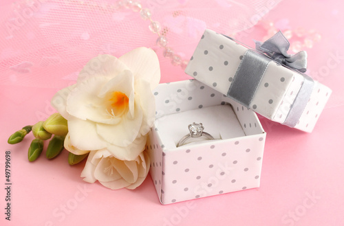 Photo: Beautiful box with wedding ring and flower on pink background Beautiful box with wedding ring and flower on pink background