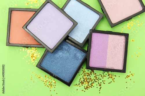 Photo: Beautiful bright eye shadows on green background Beautiful bright eye shadows on green background