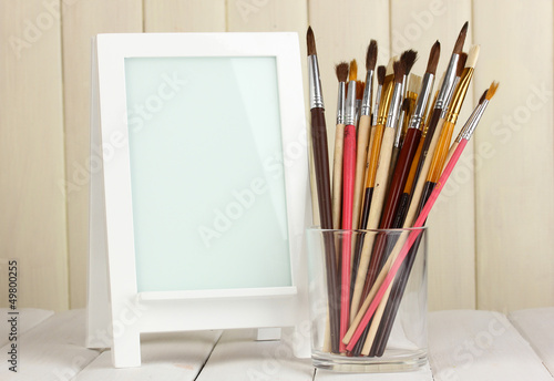 Photo: Photo frame as easel with artist's tools on wooden background Photo frame as easel with artist's tools on wooden background