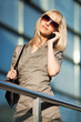 Blond woman calling on the phone against office windows