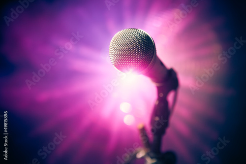 Photo: microphone on stage against purple rays microphone on stage against purple rays