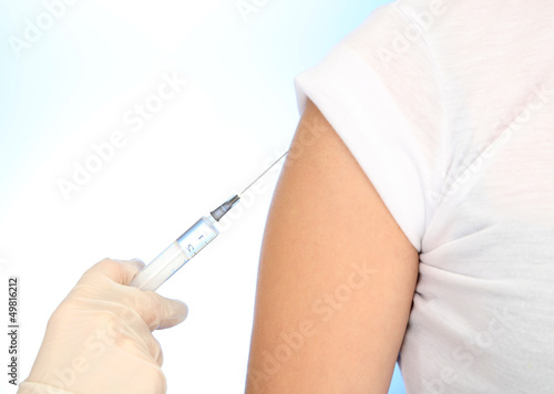 Photo: Doctor holding syringe with a vaccine in the patient shoulder, Doctor holding syringe with a vaccine in the patient shoulder,