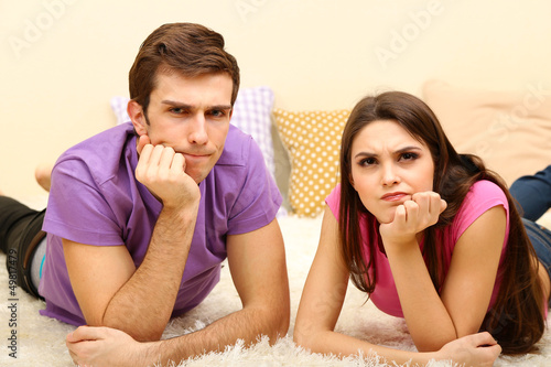 Photo: Young couple lying on carpet at home Young couple lying on carpet at home