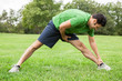Athletic man stretching legs in a field