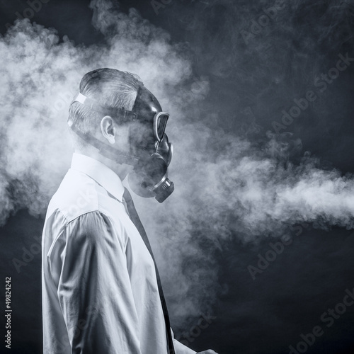 Photo: a man in a gas mask goes through the smoke a man in a gas mask goes through the smoke