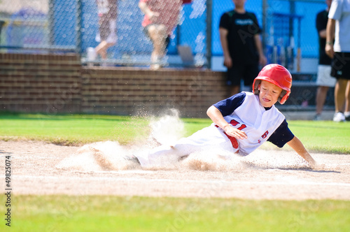 Photo: Little league baseball player sliding home. Little league baseball player sliding home.