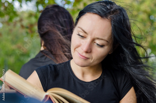Photo: Woman smiling as she reads a book Woman smiling as she reads a book