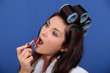 Woman in rollers applying lipstick