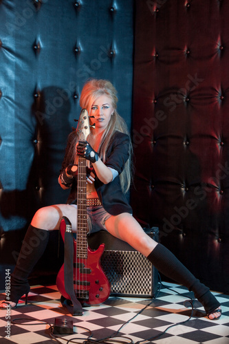Photo: blonde girl with a guitar on a dark background blonde girl with a guitar on a dark background